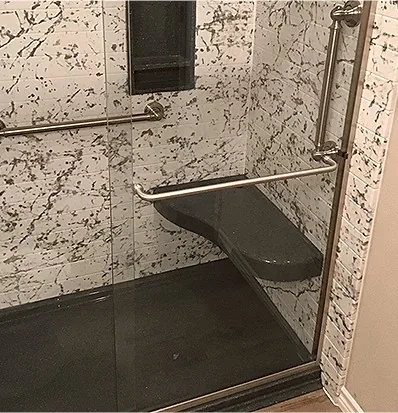 A solid surface shower with a marble pattern, a fold-down seat and stainless grab bars