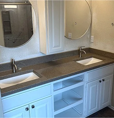 A double vanity with round mirrors and a stone countertop