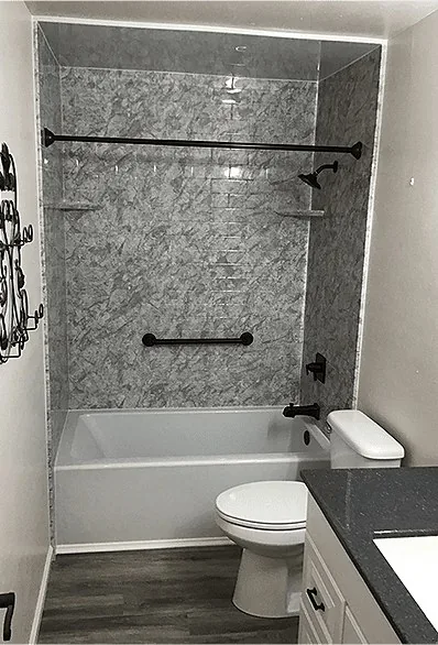 A tub and shower surround in a grey stone pattern